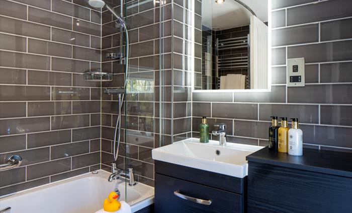 A bath with overhead shower in a luxury bathroom at a hotel.